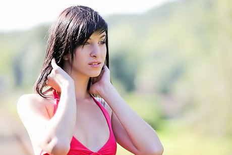 Brunette in a red dress is showing her long legs on train tracks